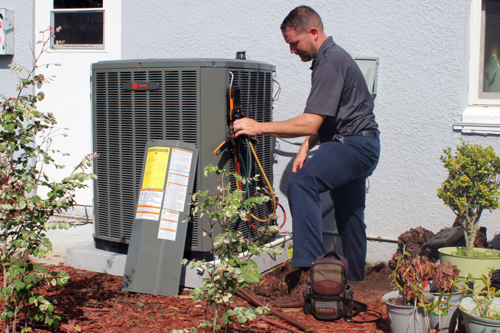 Repair man taking a look at an open air conditioning unit.