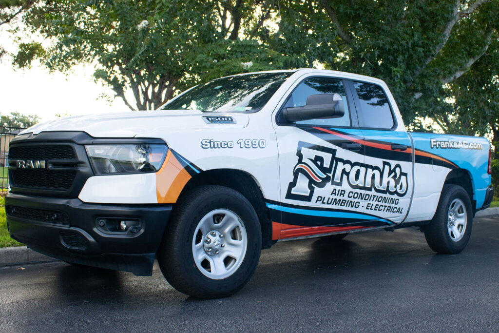 A Franks AC truck parked next to a tree